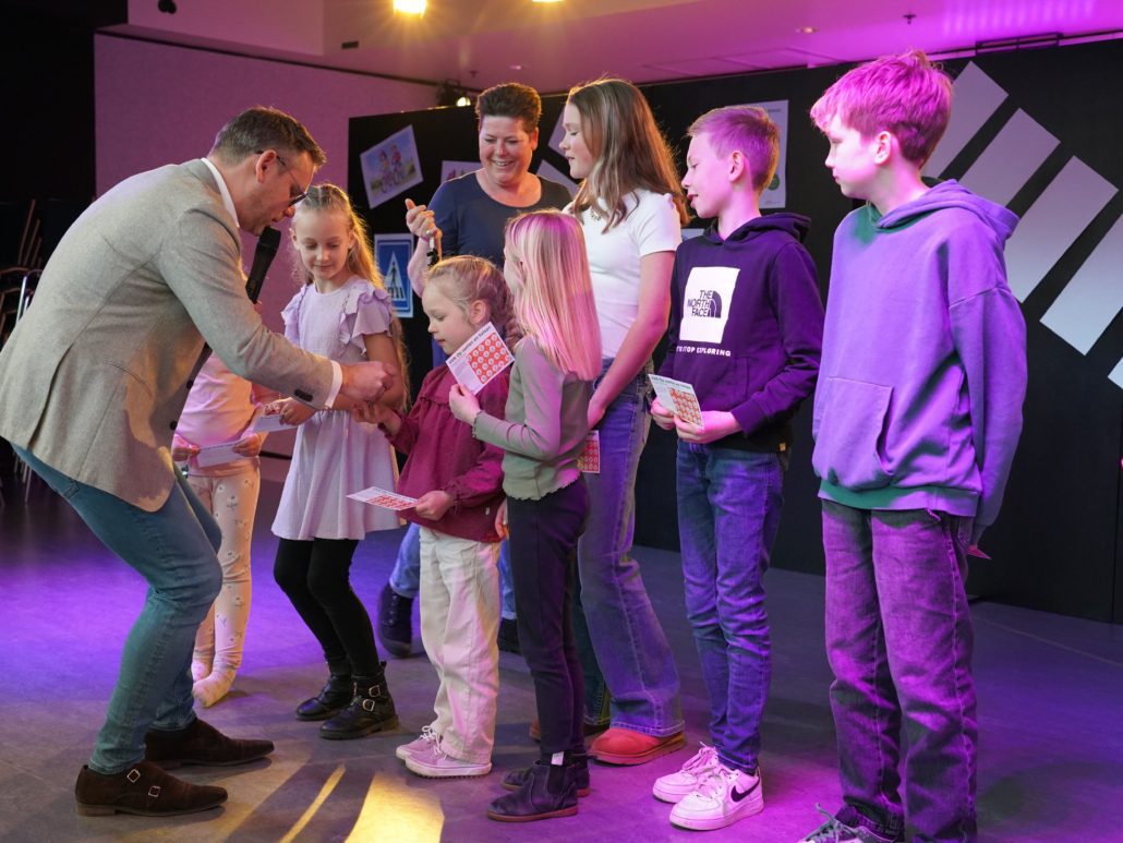 Kinderen ontvangen sleutelhangers op podium